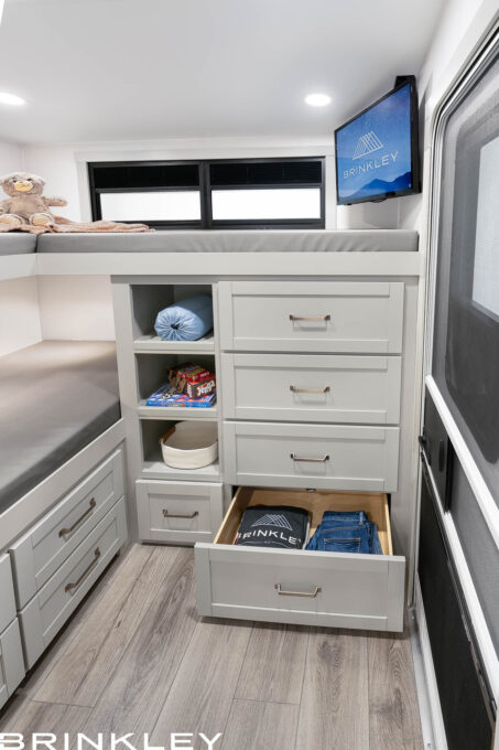 | Model Z 2810 Fifth Wheels 38 Integrated bunk bed ladder and dresser in a Brinkley Model Z 2810 Fifth Wheel, featuring four storage cubbies built into the steps and a white four-drawer dresser for maximum organization.