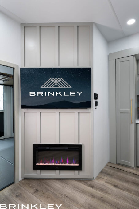 | Model Gx Toy Hauler Line 81 For the TV & Entertainment Wall image (Model-Gx-3500x-Fifth-Wheels-Living-Room-TV-Entertainment-Wall-2026-Brinkley-RV-0559.jpg) you currently have selected in the WordPress media library, here are a few alt text options:
Option 1: Descriptive & SEO-Rich (Recommended)
"Interior view of the Brinkley Model Gx entertainment center featuring a 50-inch Smart 4K UHD TV on a swivel mount above a built-in 5,000-BTU electric fireplace.