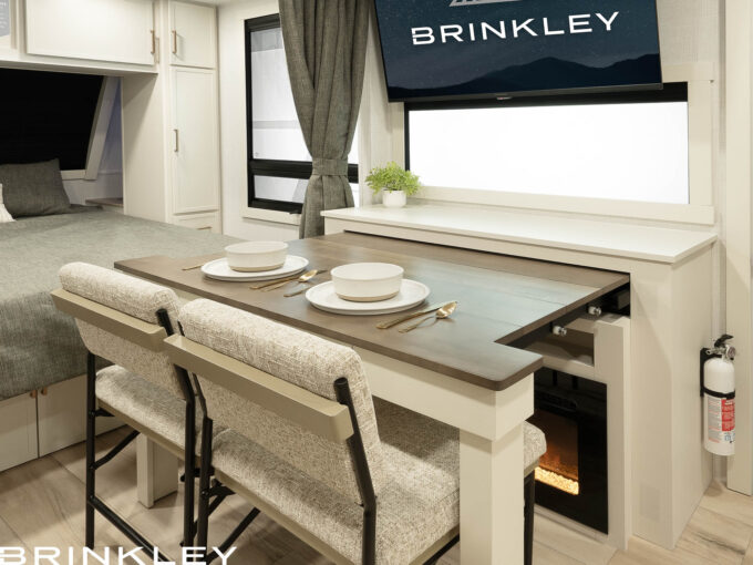 | Model I 235 Travel Trailers 15 Pull-out dining table in the Brinkley Model I travel trailers, demonstrating smart design and versatile living space. The solid hardwood table expands when needed to a table or desk and features a built-in utensil drawer with heavy-duty glides, maximizing functionality in a luxury travel trailer. When not needed it takes up almost not space maximizing living space.