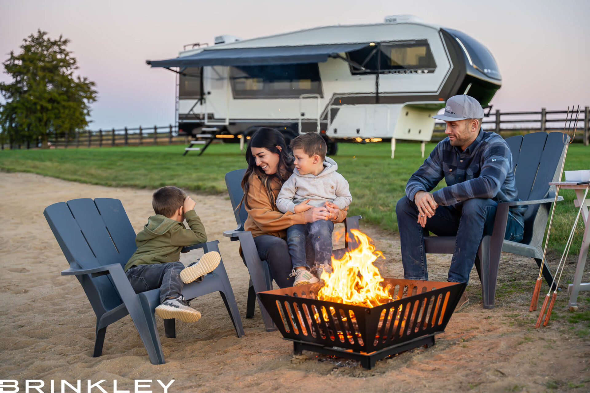 | Model Z Fifth Wheel Line 78 Luxury Fifth Wheel RV RVing with a family around a campfire on a beach. Camping on a warm summer night.