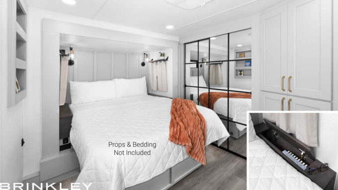 | Model Gx Toy Hauler Line 87 Interior of a Brinkley RV Model Gx 3500x bedroom featuring the optional queen-size bed flanked by two nightstands with built-in storage compartments, surrounded by windows.